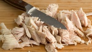 Featured | Close view of chopped turkey on a wood cutting board with a knife | Turkey Soup from Leftovers Recipe