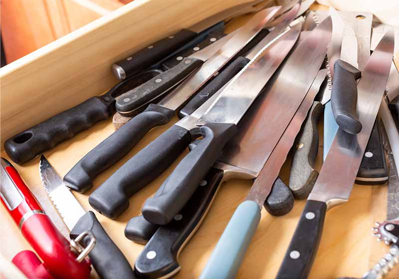 A view of a drawer full of knives and other sharp kitchen utensils