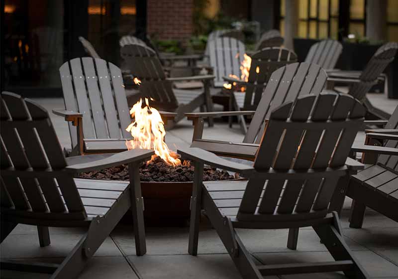 Low angle view of a fire pit surrounded by a circle of Adirondack chairs