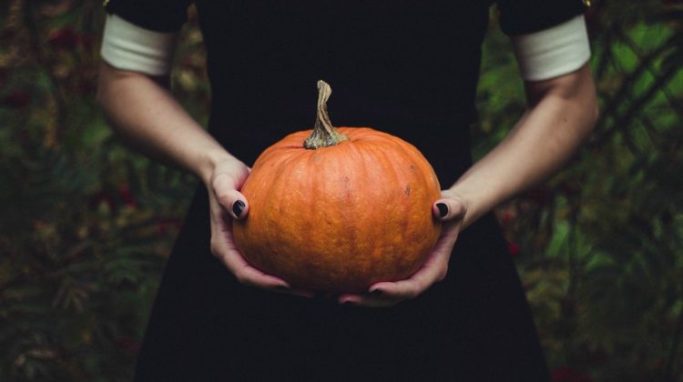 Featured | Woman holding pumpkin | Old Halloween Superstitions And Symbols From Around The World