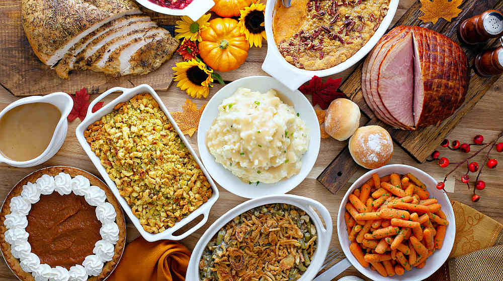 Thanksgiving table with roasted turkey, sliced ham and side dishes | Thanksgiving Table Ideas | This Is Everything You Need For A Perfect Thanksgiving Day