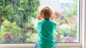 Adorable little blond child sitting near window and looking on raindrops | Rainy Day Activities | Fun Things For You And Your Kids To Do Indoors