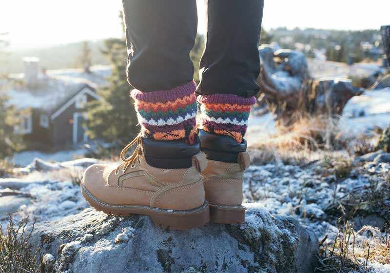 Male legs in black pants and hand knitted wool traditional ornament socks | winter boots