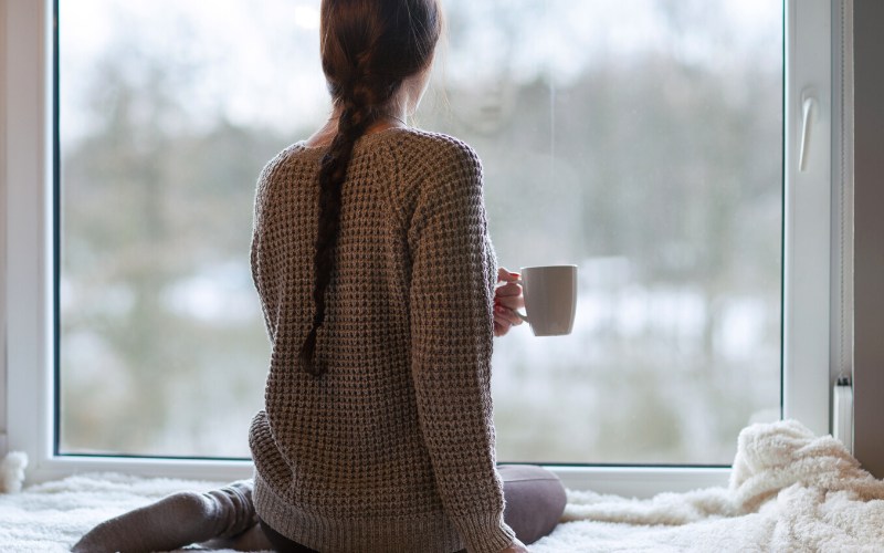 thoughtful young brunette woman book cup | winter storm warning today