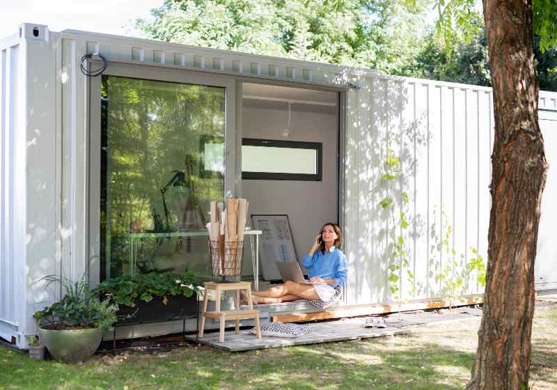 Mature woman working in home office in container house in backyard | Container Homes You Wish Were Your Own!