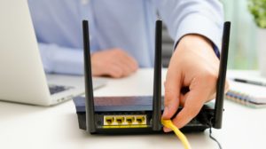 Man plugs ethernet cable into the wifi router | How to Speed Up WiFi On A Budget | how to speed up internet | Featured