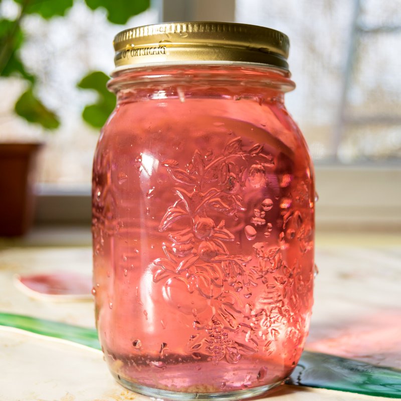 jar pink liquid on table | how to distill rose essential oil
