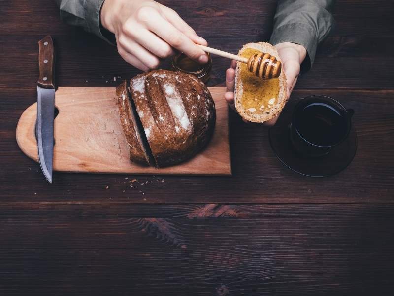 top-view-female-hands-make-sandwich-of-rye-bread | honey