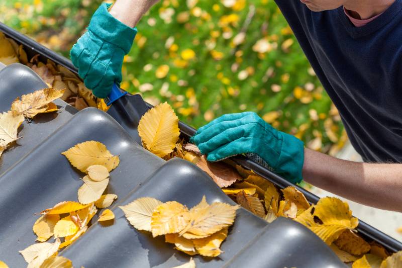 man-cleaning-gutter-autumn-leaves | Fall Home Maintenance Checklist: How To Prepare Your Home For Fall