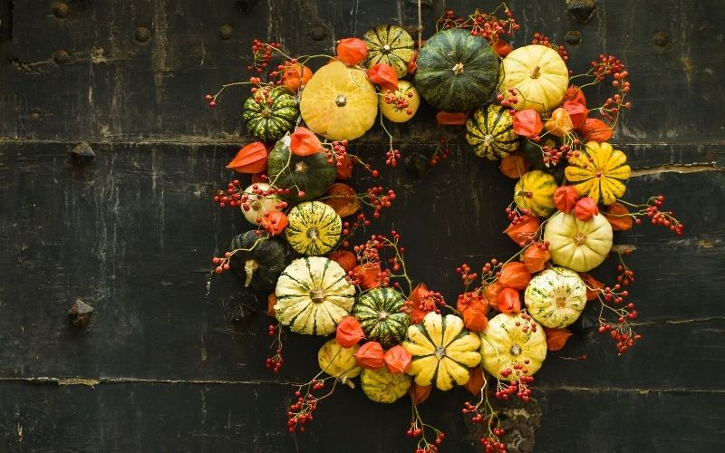 handmade wreath of small pumpkins and zucchini on a vintage door | home decor