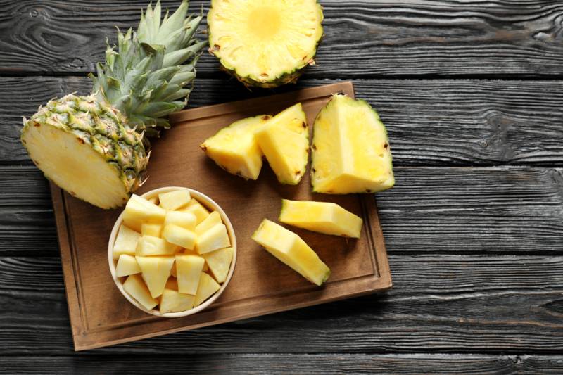 wooden-board-fresh-sliced-pineapple-on | A Homesteader’s Guide To Canning Pineapple | how to can pineapples