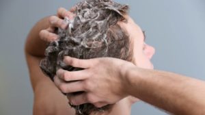 young-man-washing-hair-on-color | Homemade Shampoos For Hair Growth and Hair Loss | Featured