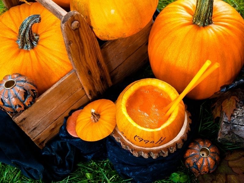 Open halloween cocktail in pumpkin with Jack o Lantern around | ## Halloween Punch Recipes To Serve At Your Home Party