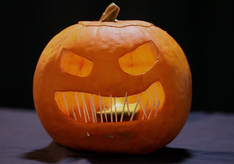 Scary faced Jack-O-Lantern with flickering candle lighting the inside 