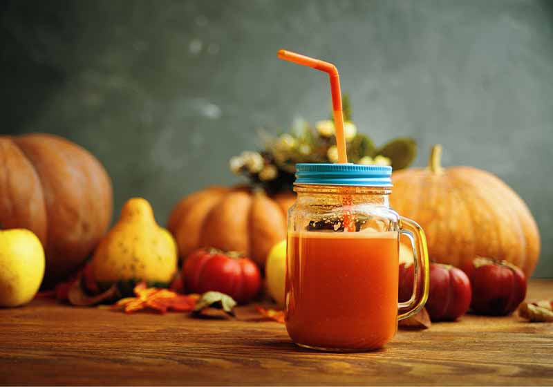 Mason jar pumpkin juice with tube placed on a wooden table | picnic ideas for family