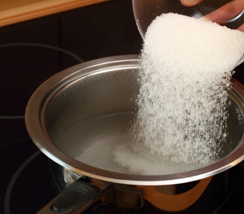 Pouring sugar into saucepan with boiling water | peaches