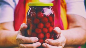 Senior woman holding a jar of cherry | How To Make Homemade Canned Cherries | featured