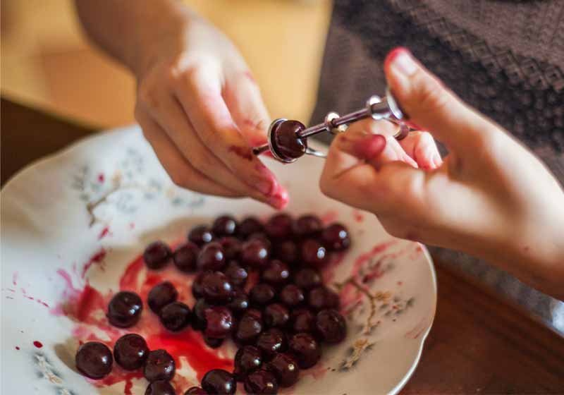 Women's hands remove bones from the cherry with a special device | how to can cherries
