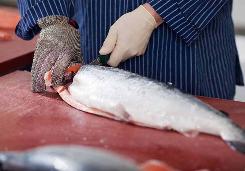 close-up of a worker cutting salmon on a board | how to fillet fish the easy way