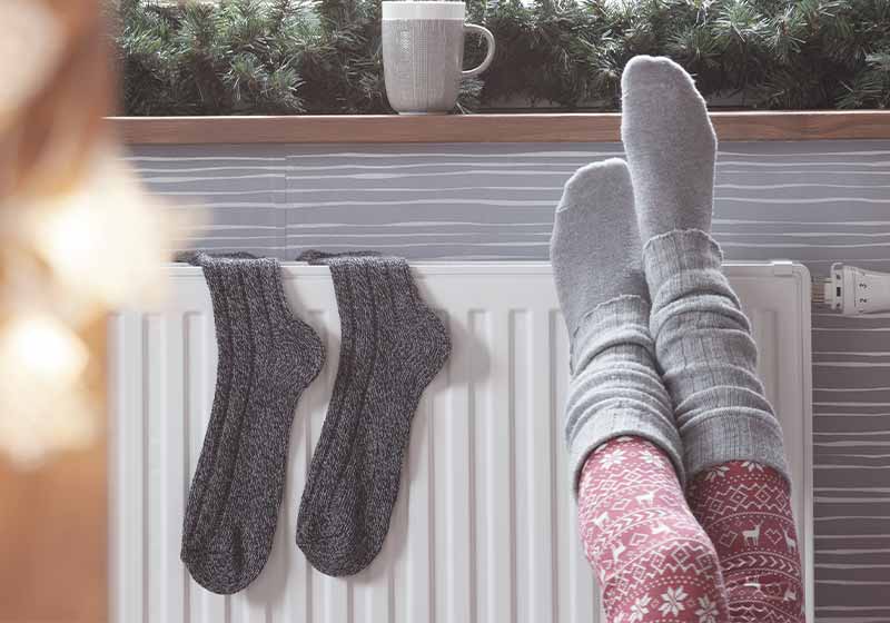 Woman warming up with feet on heater | snow hacks