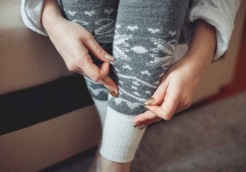 a woman puts on warm gray woolen leggings | cold weather hacks