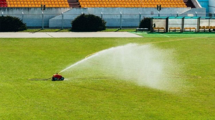 Red mobile sprinkler watering | Tractor Sprinkler FAQs: How Does It Work? | Featured
