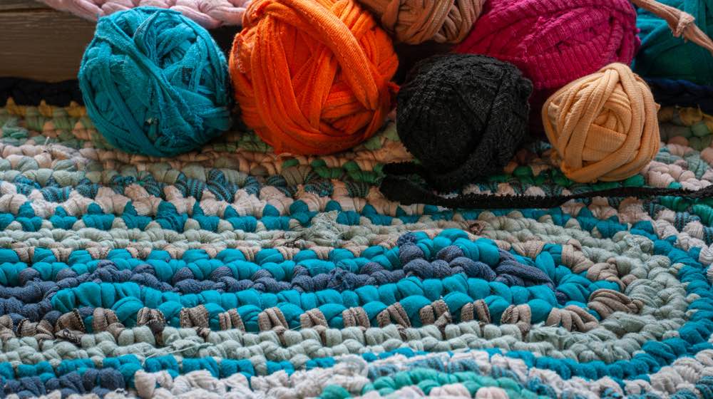 https://homesteading.com/wp-content/uploads/2022/05/pink-rag-rug-with-balls-of-tshirt-wool.cosy-weekend-Rag-Rug-How-To-Make-a-Rug-Rag-Rugs-Infographics.jpg