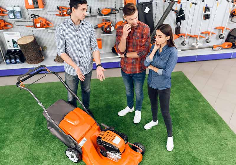 A consultant in a garden tools store shows a guy and a girl a lawn mower | black friday deals