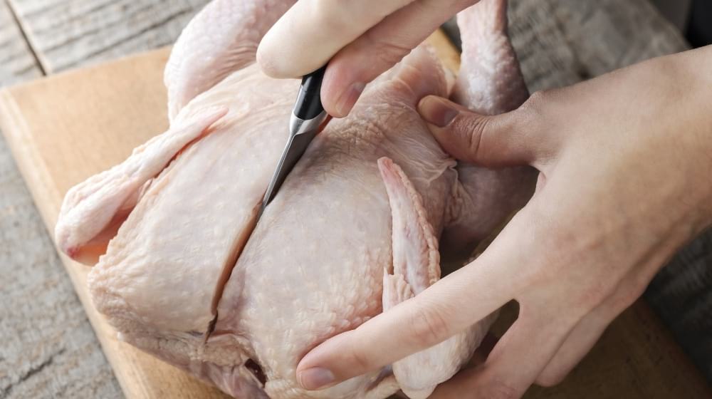 A girl knives a raw chicken into pieces | How To Debone Chicken Like A Pro | Featured