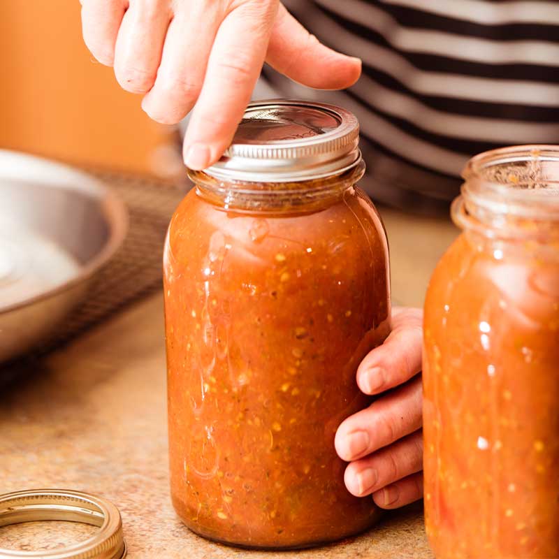 Band being screwed onto the jar as part of the canning process | canning