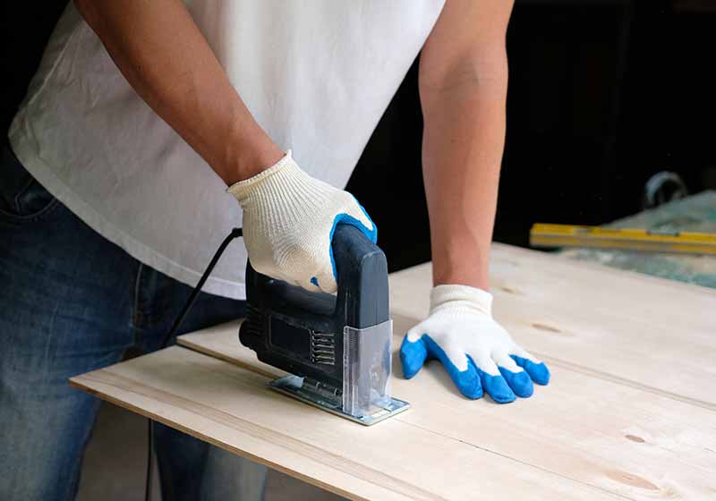 Carpenter is sawing a plywood sheet with jig saw machine in carpentry workshop | rabbit care