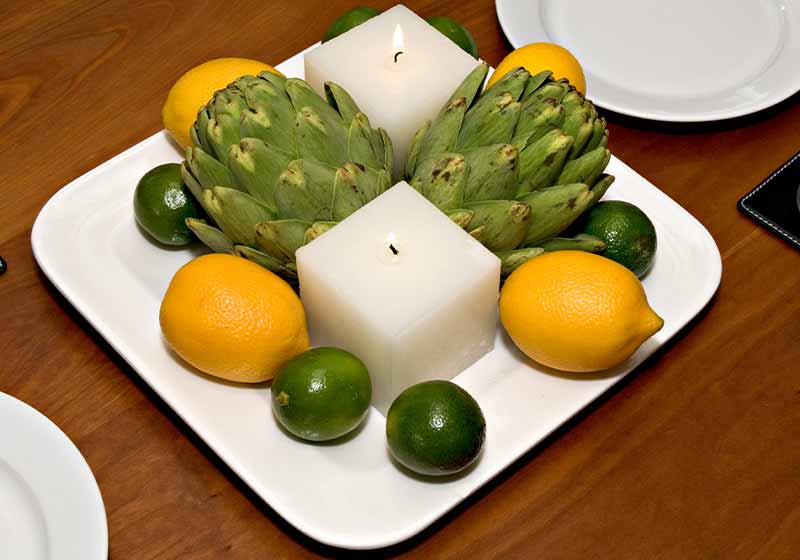 Contemporary centerpiece with candles, artichokes, lemons and limes | thanksgiving decor