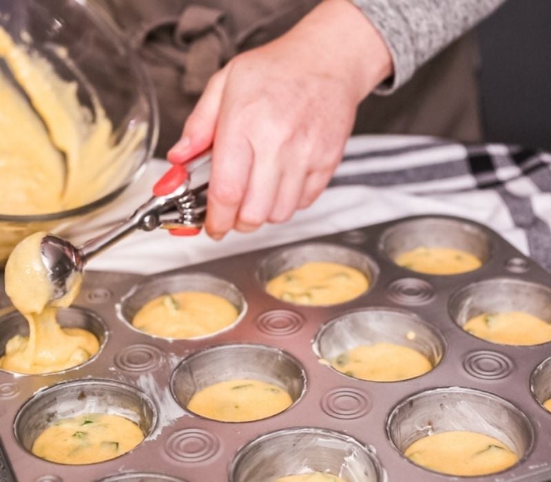 Filling metal muffin pan with cornbread batter | oatmeal treats for chickens
