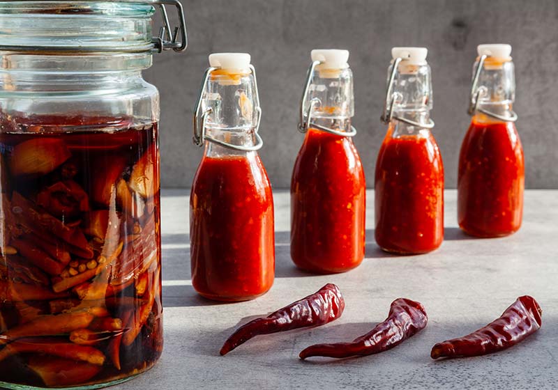 Four small bottles of chili hot sauce made from fermented dry de Cayenne chilies | homemade hot sauce