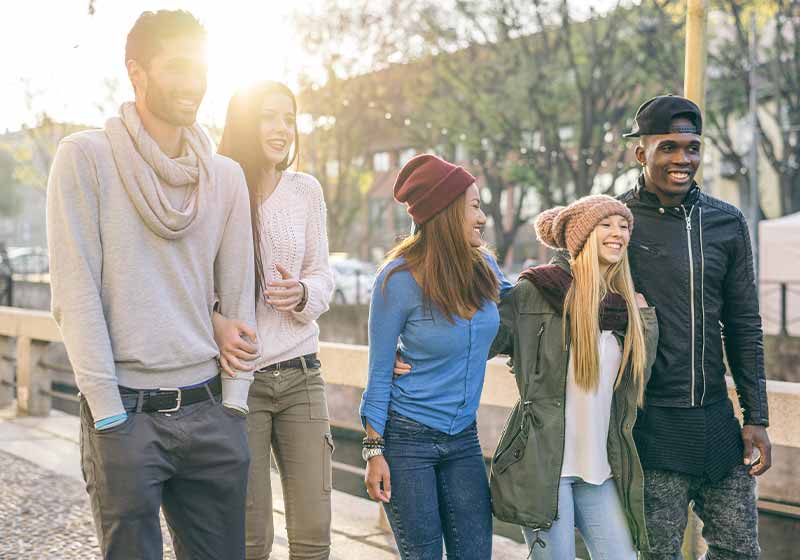 Group of multi-ethnic friends walking on the streets and smiling | winter walking tips