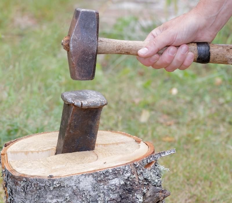 Hand holding a sledgehammer hit a wedge | splitting maul 