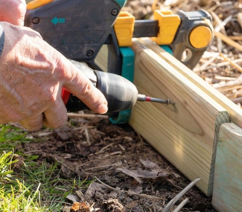 Hands of a man make a piece-of-wood-assemble with screw machine | solar powered stock tank heater