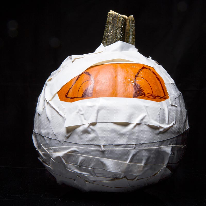 Pumpkin posed as a mummy wrapped in white duct tape | jack-o-lantern carving ideas