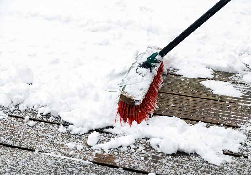 a broom sweeps the snow for prevention | snow hacks