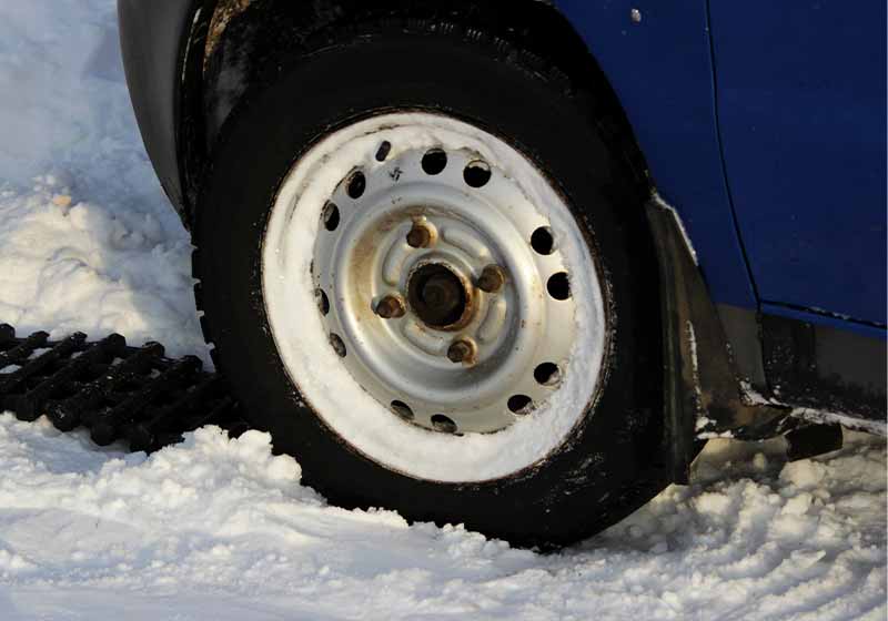 black anti-slip mat of a rectangular shape is placed under the wheel of a low-leveled car | life hacks