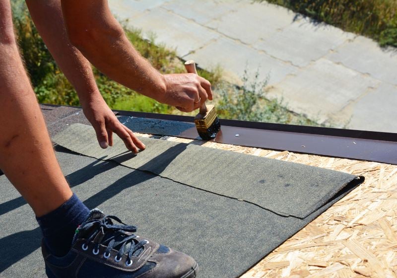 building contractor installing underlayment layer bitumen | log cabin kits