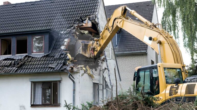 A digger demolishing houses for reconstruction | Eminent Domain: How It Is Affecting And Afflicting Homesteaders