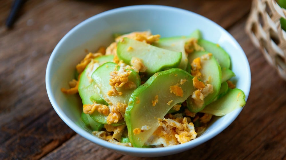 Fresh chayote fruits (Sechium edulis) stir fried with egg and garlic in bowl on wooden background | Healthy Sauteed Chayote Squash Recipe | featured