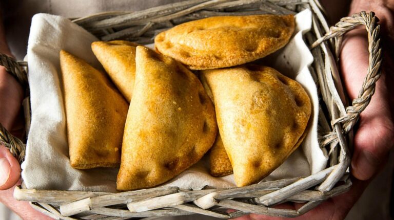 Featured | Man chef holding in hands a wicker basket with freshly baked vegetarian empanadas | Sweet and Savory Hand Pies
