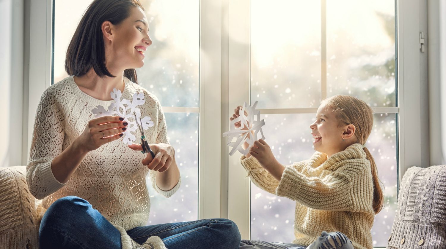 Feature | Happy loving family sitting by the window and making paper snowflakes for decoration windows | Indoor Activities For Kids This Winter | Snow Day