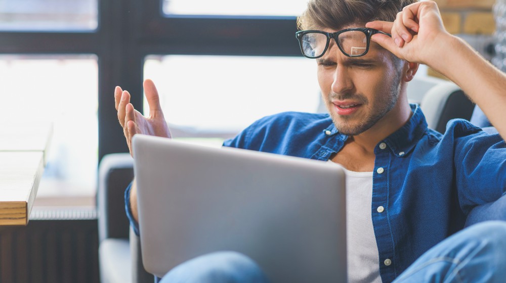 sad man looking into his laptop | Why Is My Laptop Slow? (And How To Fix It On A Budget) | why is my laptop slow