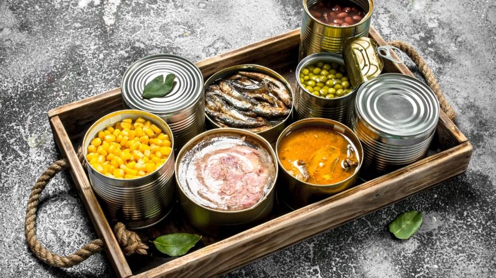 various-canned-products-in-tin-cans-on-a-wooden-tray | How To Open A Can Without A Can Opener | Featured