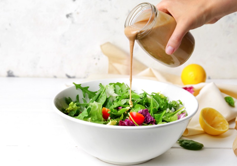 woman pouring tasty tahini jar onto | whole foods plant based diet