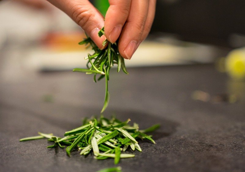 womans hand holding rosemary leaves falling | best tonic syrup for health
