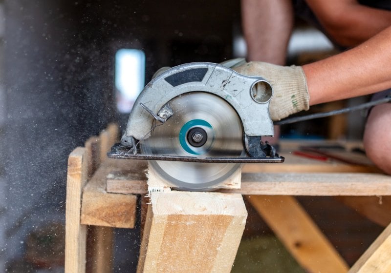 worker saws wooden beam building house | where can i learn basic carpentry skills